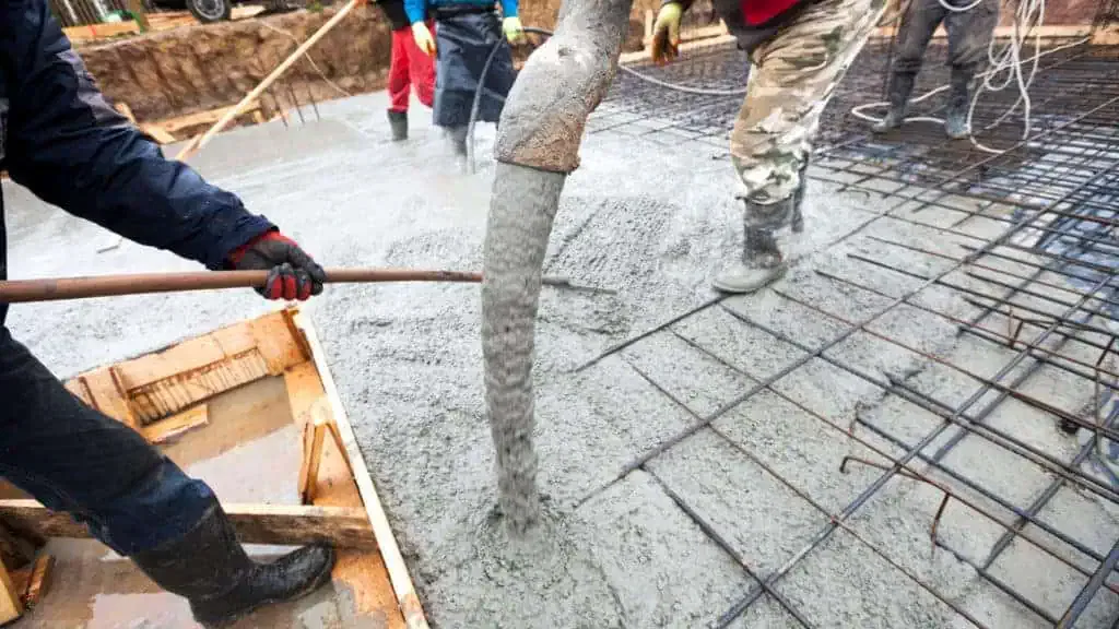 A group of construction workers pouring concrete on a concrete floor.