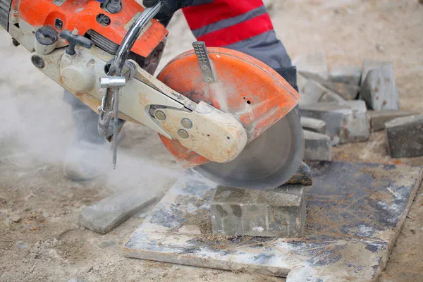 A man using a circular saw for asphalt grinding.