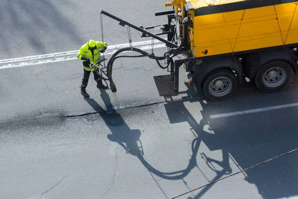 machine pouring concrete over crack on asphalt