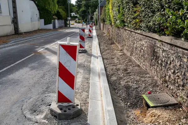 Construction of a road in France including the installation of curbs and gutters.