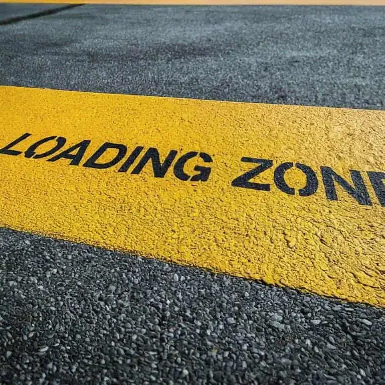 A yellow road marking on asphalt indicates a loading zone.