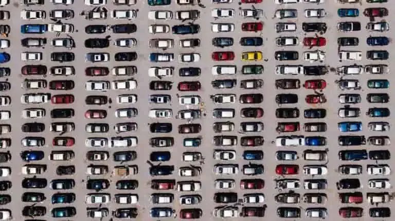 Aerial view of a crowded parking lot with rows of parked cars in various colors.
