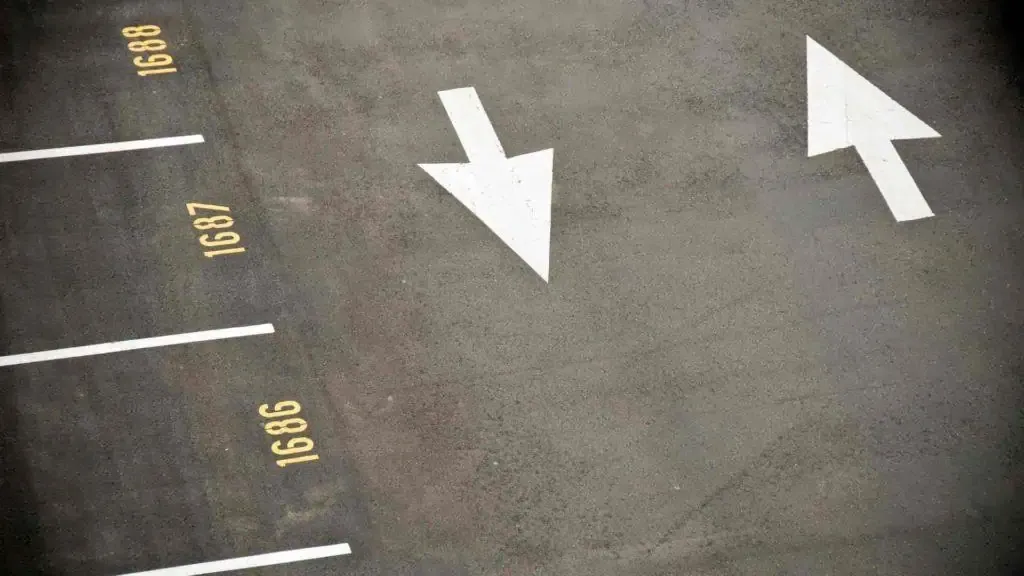 Two arrows pointing in different directions on a parking lot.