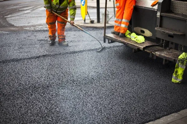 finishing touches to asphalt road repair