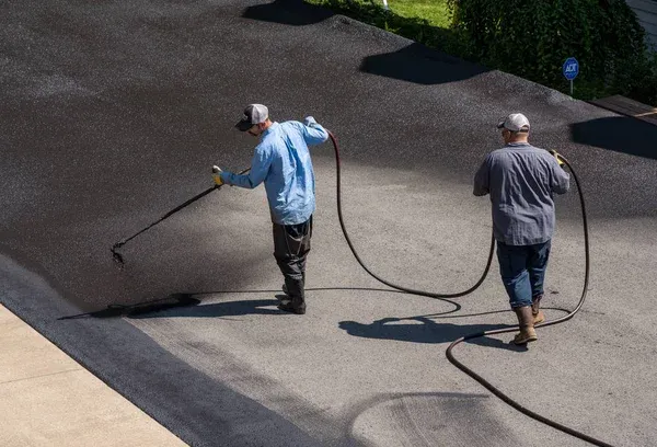 contractors putting seal coat on asphalt