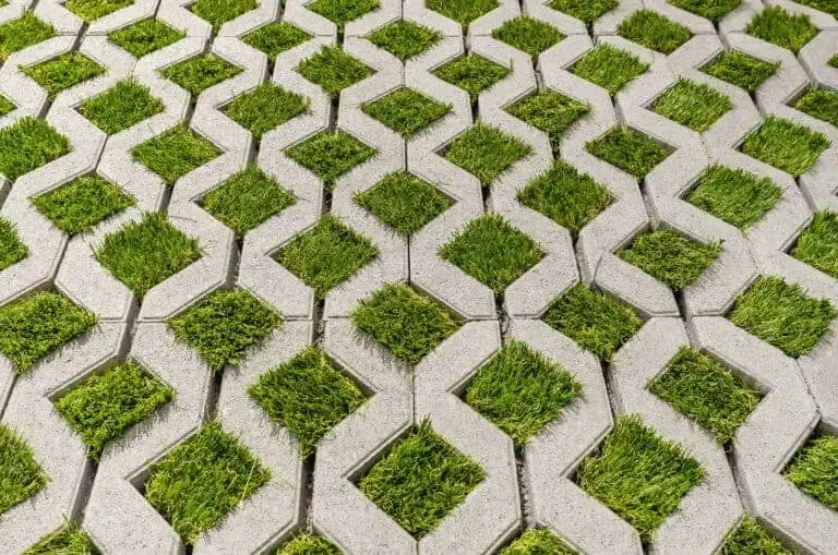 A pattern of interlocking concrete pavers with diamond-shaped grass patches.